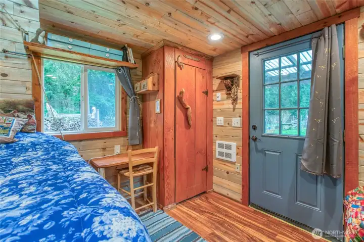 Interior view toward the door, highlighting wood finishes, and glimpses of the outdoors.