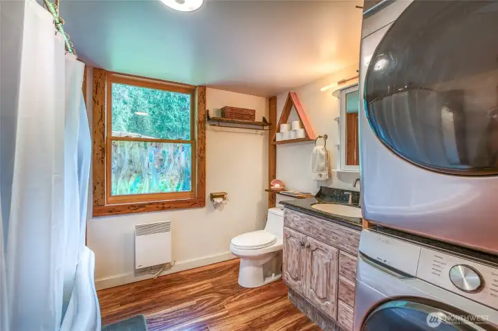 Bathroom featuring a soaking tub, nicely sized window, and a conveniently placed washer and dryer.