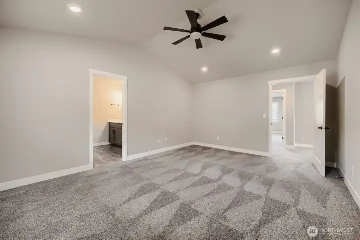 Generously sized primary bedroom offers vaulted ceilings, plush carpeting, ceiling fan, abundant natural light, and flexible living space. Generously sized primary bedroom offers vaulted ceilings, plush carpeting, ceiling fan, abundant natural light, and flexible living space.