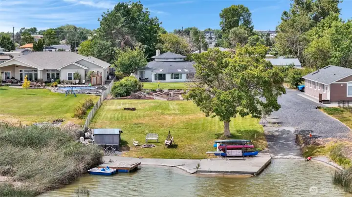 The gravel driveway is shared, but the boat launch is yours! The orange cones show where the property boundary is, and you have a storage shed for your water toys down by the cozy firepit.
