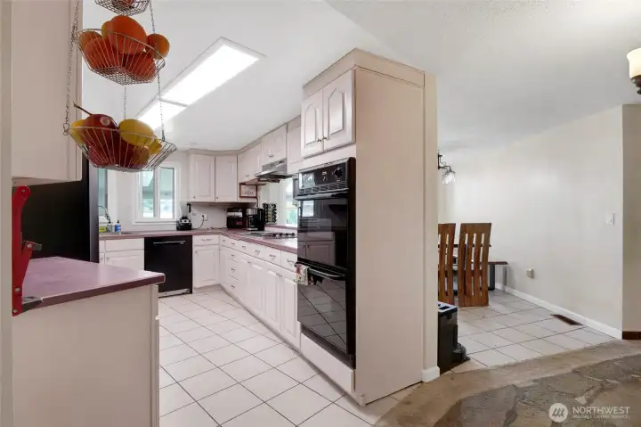 Around the corner is the large kitchen facing the back yard and sunroom. There's ample counter space and a double oven for multiple casseroles to be baking at the same time. Dining room is on the other side with a pass-through to the kitchen.