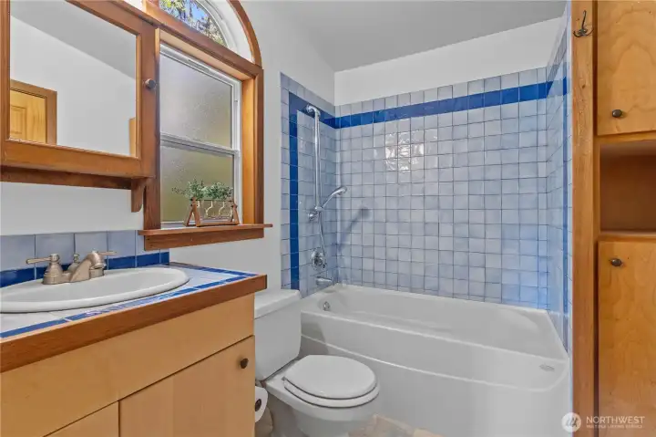Updated full bathroom featuring tile shower surround and natural wood finishes. Updated full bathroom featuring tile shower surround and natural wood finishes.