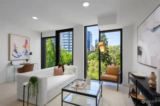 Living area features operable floor-to-ceiling windows, engineered hardwoods, ceiling Mitsubishi mini-split, and ample space for a home office.