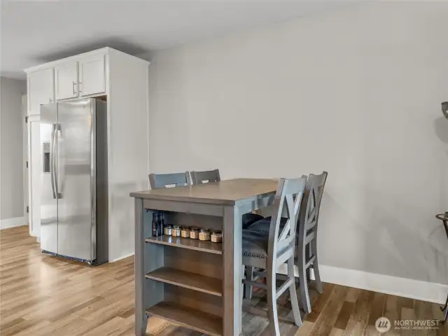 Bright dining area with seamless flow to the kitchen, featuring a stainless steel fridge and plenty of space for meals and gatherings.