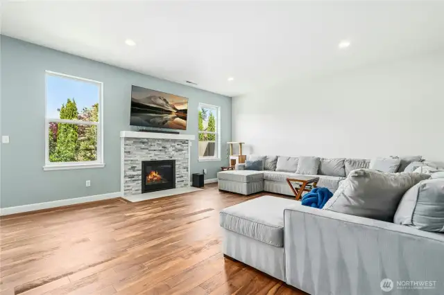 Open concept family room with gas fireplace and engineered hardwood flooring.