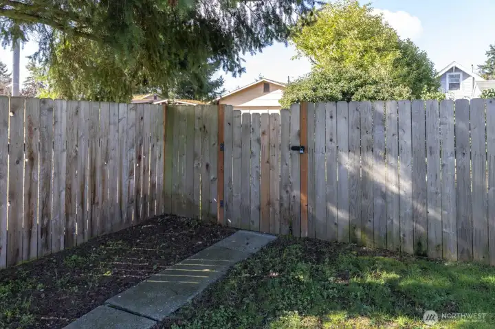 gate to back yard. A chain link fence is behind the wood fence.