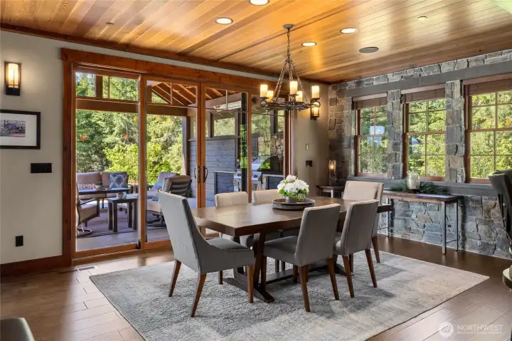 Dining room that opens to covered patio with stone wall and sonos speakers