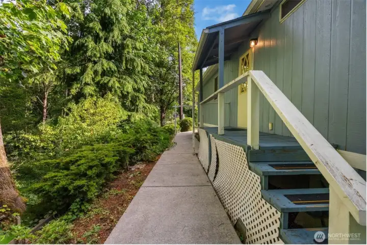 A great sidewalk runs along the back of the home next to the forest, giving you an easy place to walk, tend plants, or simply enjoy the greenery up close.