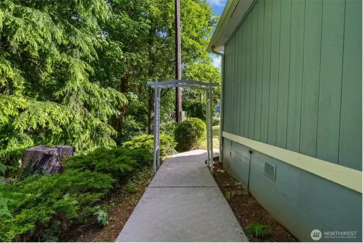 The sidewalk continues around to the front of the house, creating an easy flow between the front entry, back porch, and forest-side outdoor areas.