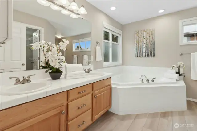 The primary's 5-piece bath with jetted tub. The stand-alone shower and toilet are tucked around to the right, and the walk-in closet is behind the door.