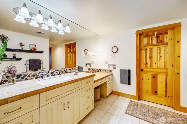 The other part of the primary ensuite bath, with a vanity seat and walk-in closet behind the door.