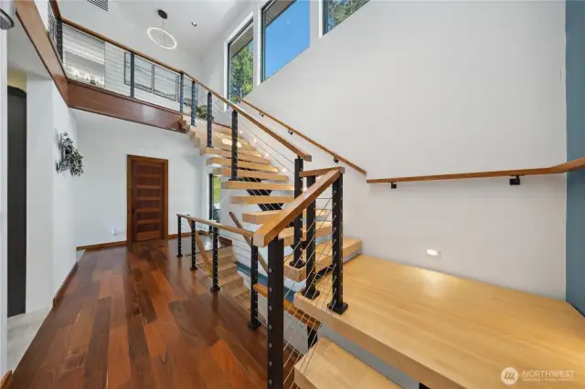 Main level staircase flowing up to the primary bedroom and loft office/ bedroom