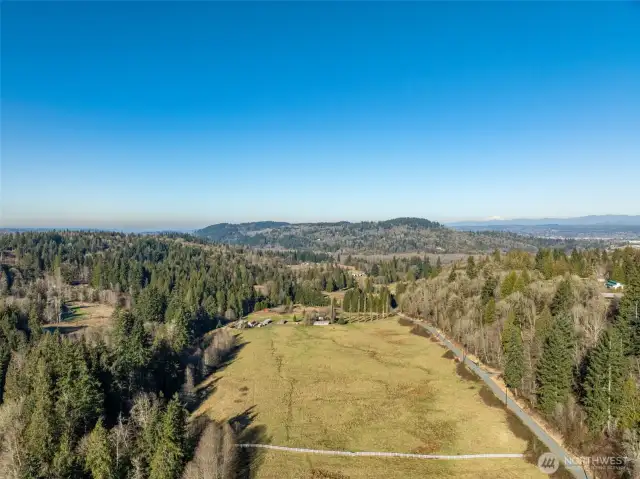 Expansive property with sweeping views of Lord's Hill and the surrounding evergreen landscape. Quiet country road access with open pastureland framed by a forested creek to the West, a gorgeous fence to the South, and the country road it abuts to the East.