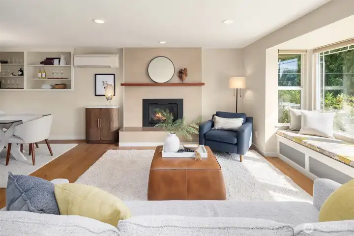 Open and airy living room with bench window seat with custom cushions and cozy gas insert fireplace.