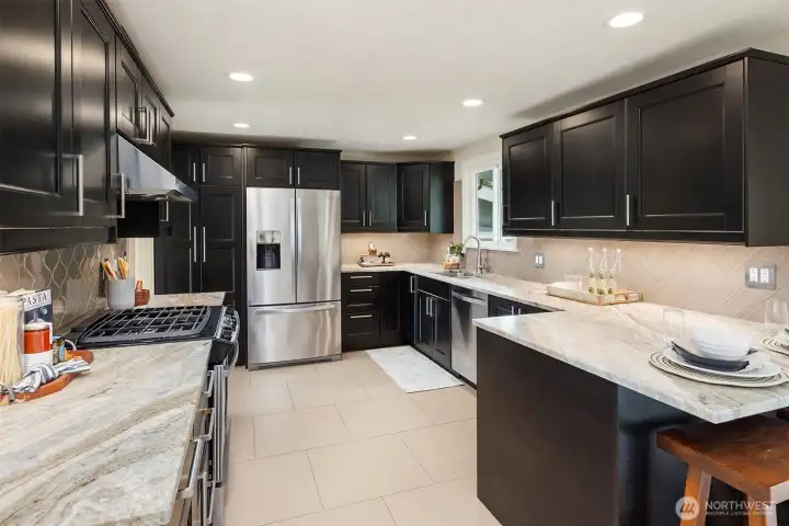 Chef's kitchen with quartzite counters, custom tile backsplash and stainless appliances.