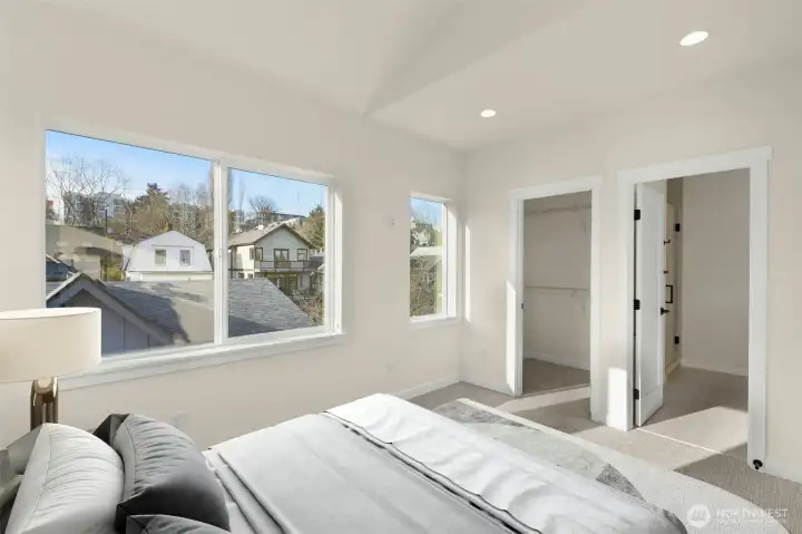 Serene primary bedroom featuring large windows and a minimalist aesthetic