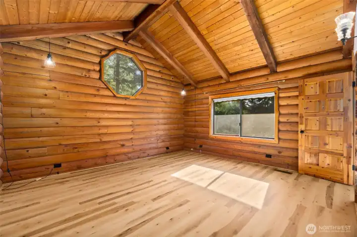 Spacious upper-level bedroom with vaulted ceilings, custom window detail, walk-in closet, and direct bathroom access — ideal as a primary suite or private guest retreat.