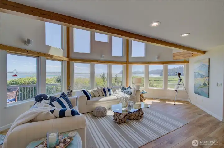 THROUGH OPENING FROM THE FOYER WALL AND YOU ARE WELCOMED BY A VAST WALL OF WINDOWS LOOKING OUT AT THE BAY IN THE EXTRA LARGE LIVING ROOM.