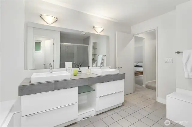 A sumptuous spa-like ensuite featuring a five-piece bath, built-in shelves, and a bench—both spacious and serene.