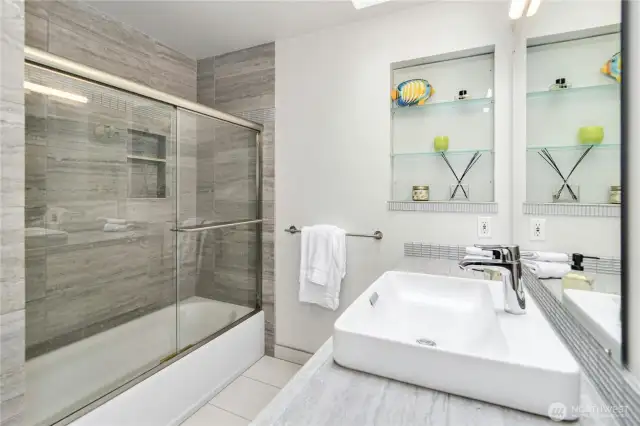 The second-floor bath features a vanity, shower, and tub, offering both style and functionality.