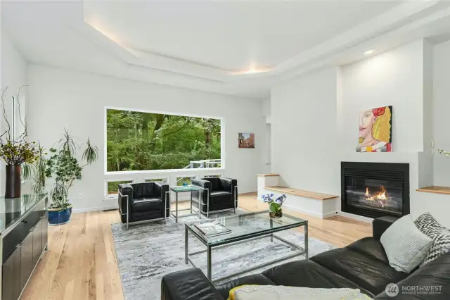 An inviting living room with a gas fireplace and oversized windows brings nature inside.