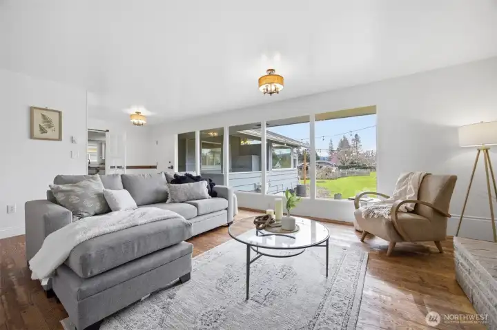 The living room has beautiful oak floors, and is very spacious with a south-facing window wall that looks out to the level rear yard and garden areas, while the natural sunlight streams inside!