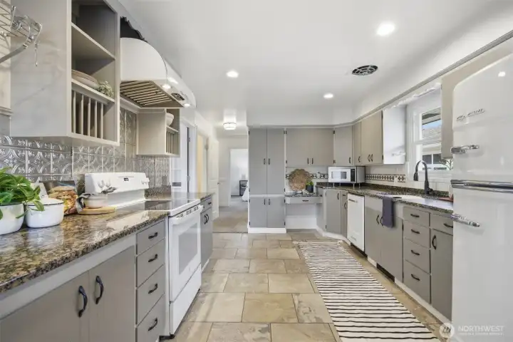 Now this is a kitchen! In keeping with the mid-century design, the updates have maintained that era! The slab granite counters are abundant, as well as the cabinet storage space and the BIG CHILL appliances (dishwasher, refrigerator and hood vent) really complete the look!