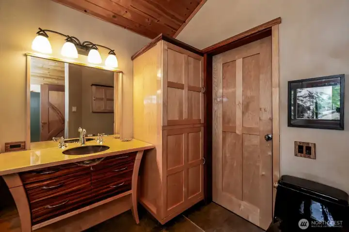 Primary bath is made of Zebra wood. Cabinet next to sink houses stackable washer/dryer.