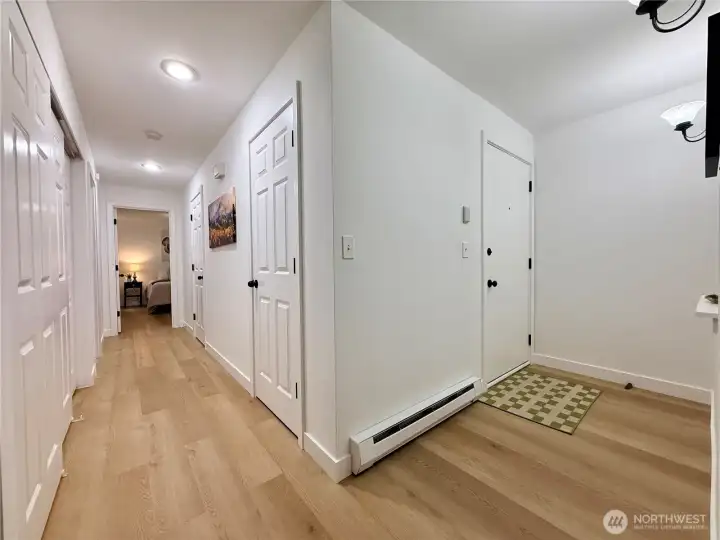 Back inside, looking at the front entrance, and the hallway with storage closets, and to the guest bathroom, and bedrooms.