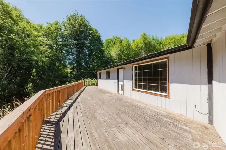 Deck that overlooks the stream Living room window on right. Door leads to livingroom and coat closet. The other 2 windows are the 2 auxiliary bedrooms. Stairs lead to lawn on the ohter side of the house.