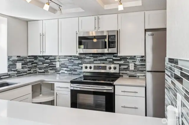 A modern tile backsplash complements the gorgeous quartz countertops.