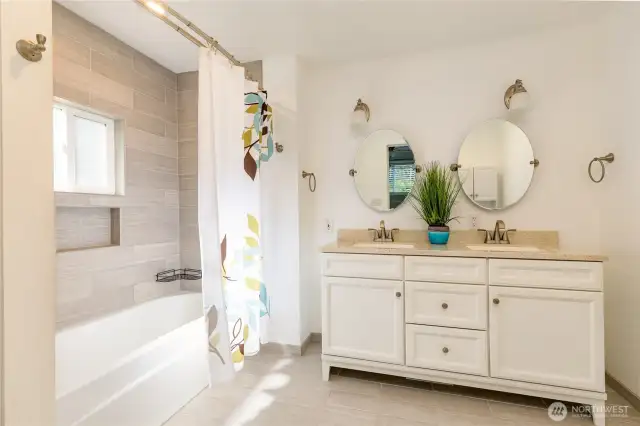 Full primary bathroom with dual sinks and beautiful tiled floor and tub surround