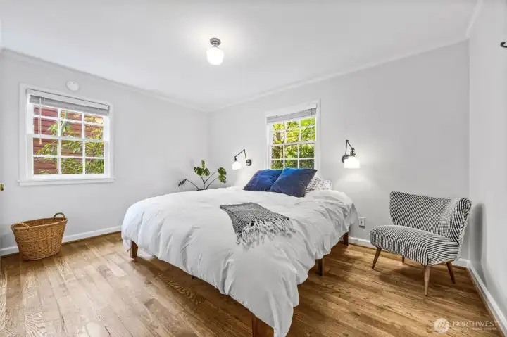 One of two bedrooms on main floor with breathtaking hardwood flooring and classic grid windows looking out to all the established greenery.