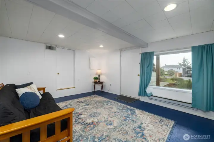 Family room with exterior entrance, concrete floors, and built-in shelving. It also has an adjacent storage area.