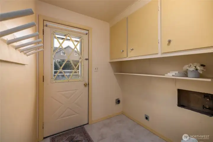 Back door enters into the laundry room with storage and shelving.