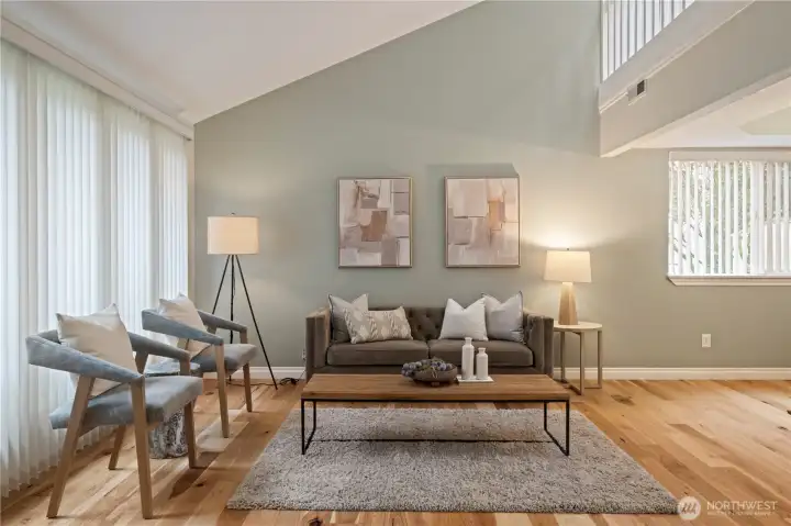 This light-filled living space feels calm and inviting, with soft, timeless hues, warm wood tone floors, and thoughtfully chosen décor that create an airy sense of comfort, balance, and understated elegance.