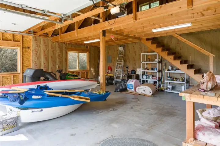 Inside the shop/garage with concrete floor and stairs to storage loft.