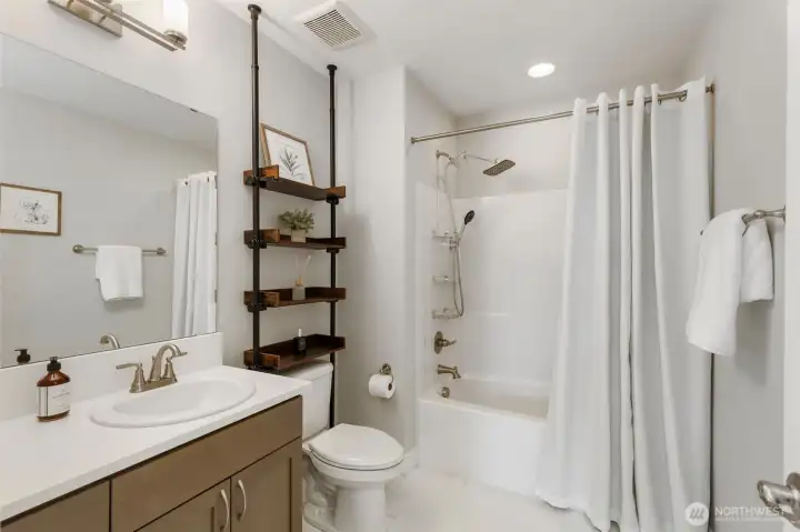 Well-appointed upper-level bath with a clean, modern design, full tub/shower combo, and stylish open shelving—ideal for everyday convenience.