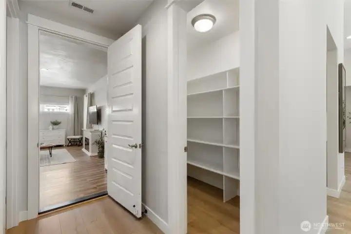 Generous walk-in pantry with built-in shelving, offering abundant storage and easy access, conveniently located just off the kitchen with a seamless connection to additional living space.