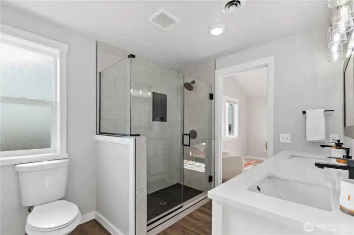 Oversized walk-in shower showcases floor-to-ceiling tile, matte black fixtures, frameless glass, and built-in niche storage for a refined spa-like feel. Oversized walk-in shower showcases floor-to-ceiling tile, matte black fixtures, frameless glass, and built-in niche storage for a refined spa-like feel.