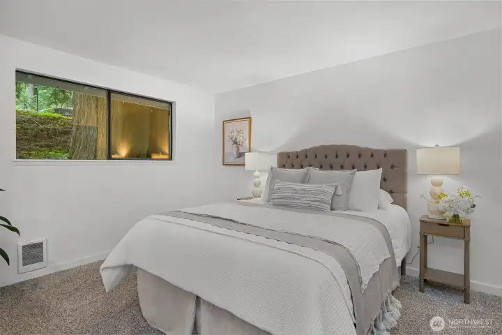 Primary bedroom offers a calm retreat with soft natural light and views of the surrounding greenery.