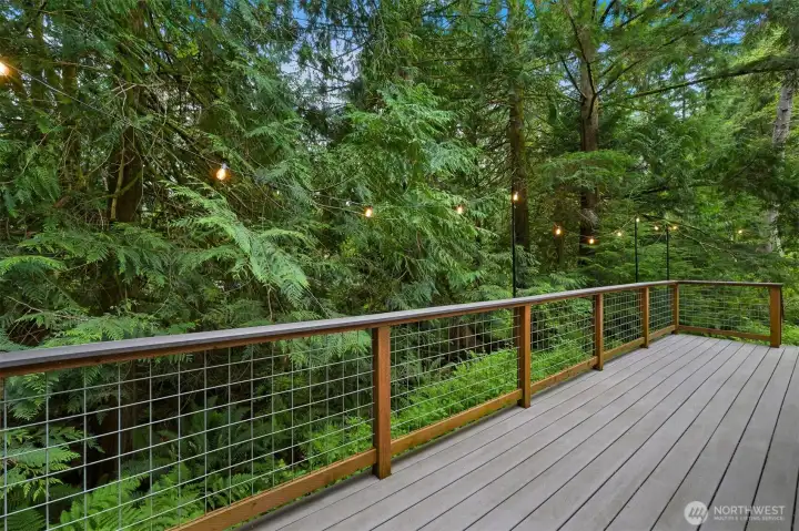 Outdoor living area extends the home’s usable space and overlooks a lush, wooded backdrop with creek.