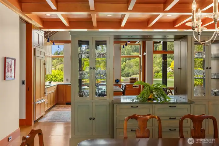 View from the elegant dining room to the kitchen through the inspired wood, granite, glass built-in buffet with accordion doors and lighting.