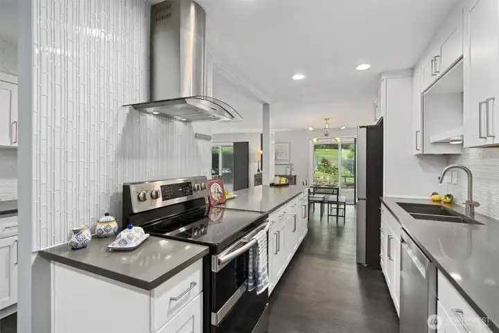 Sleek quartz counters and gleaming white tile backsplash that extends to the ceiling