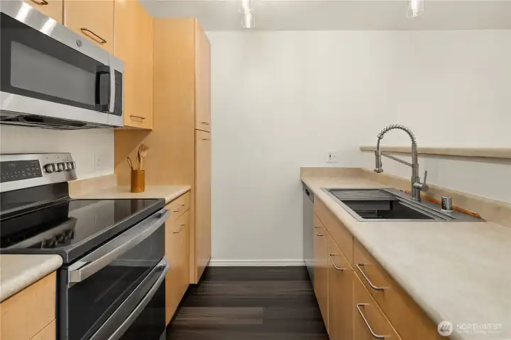 A nicely designed kitchen with pantry closet, newer flooring, and updated stainless steel appliances and sink