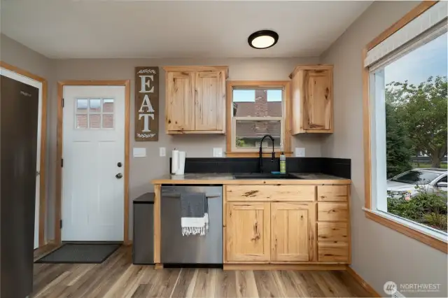 View of kitchen from front entrance. Exit door to side yard.