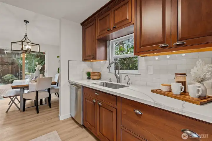 The sleek galley-style kitchen has been stylishly updated with new subway tile backsplash, a new undermount sink, a new faucet, and new quartz counters.