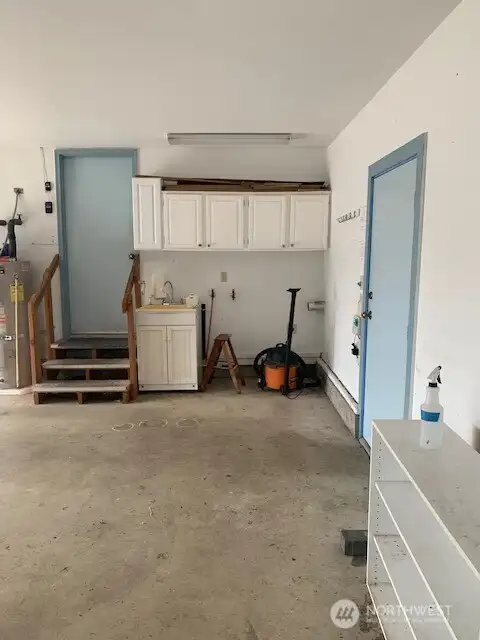 Space for a washer and dryer next to the utility sink with lots of storage above in the garage.