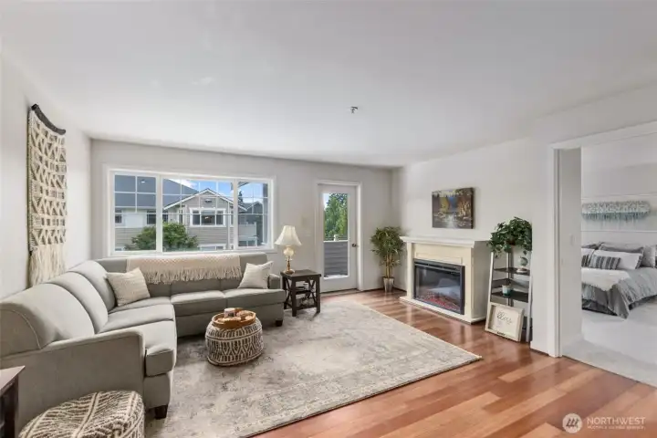 Large, bright living area with electric fireplace and balcony access Large, bright living area with electric fireplace and balcony access