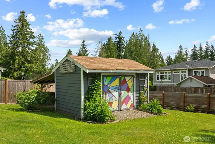 Spacious storage shed and covered storage area behind shed